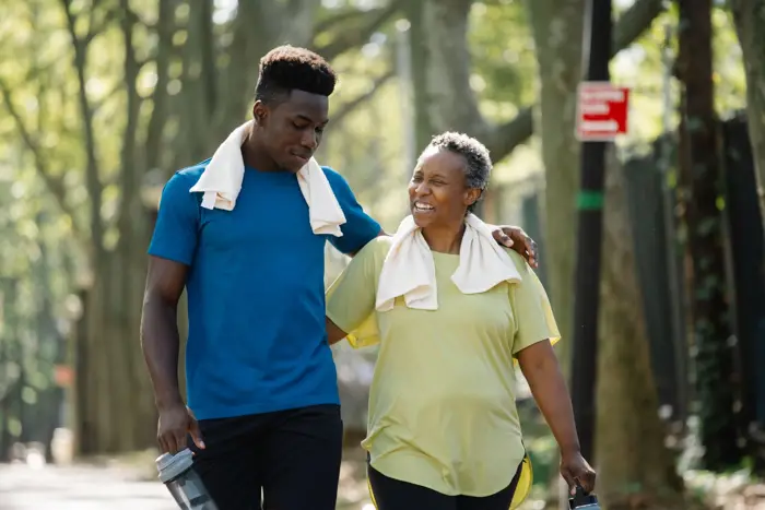 Stock photo: an older woman and a young man walking arm in arm outdoors